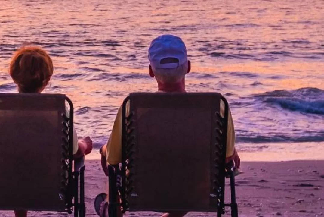 A couple watching a sunset in two beach chairs on the beach