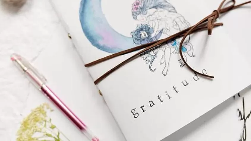 image of a small paper journal with leather rope around it and a pretty water color design on the cover