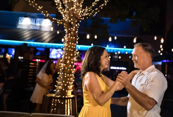 A man and a woman dance at an outdoor bar