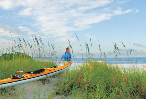 A couple walking and holding a kayak