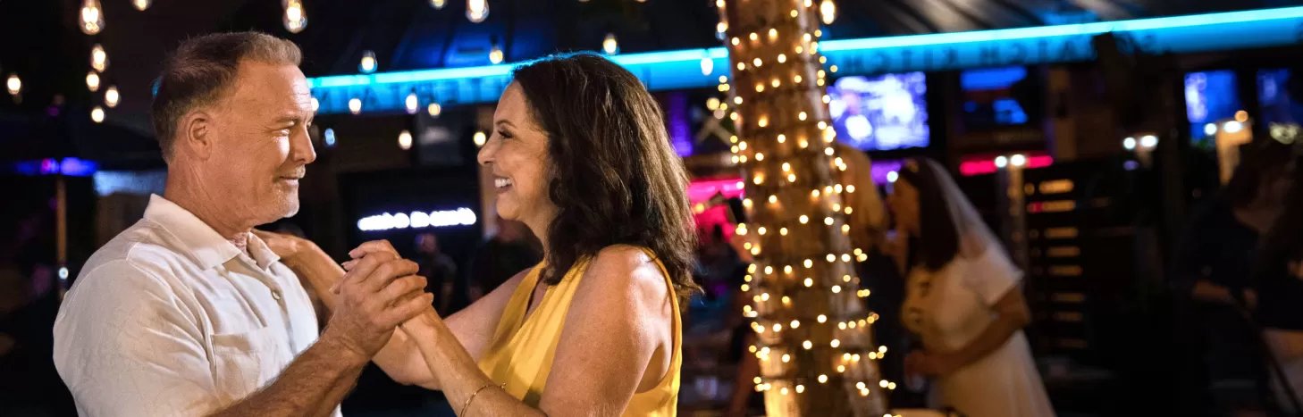 A man and a woman dance at an outdoor bar