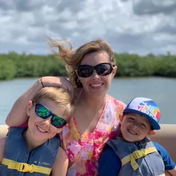 mom with two kids on boat with life vests on