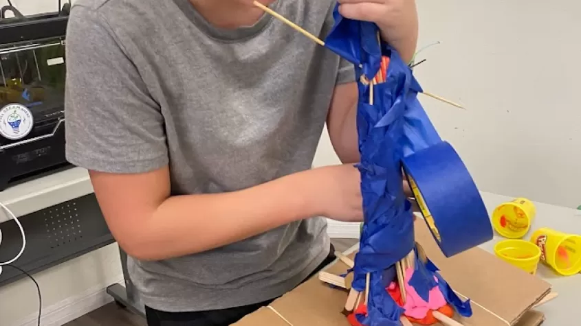 Student creating model of building ontop of earthquake simulator